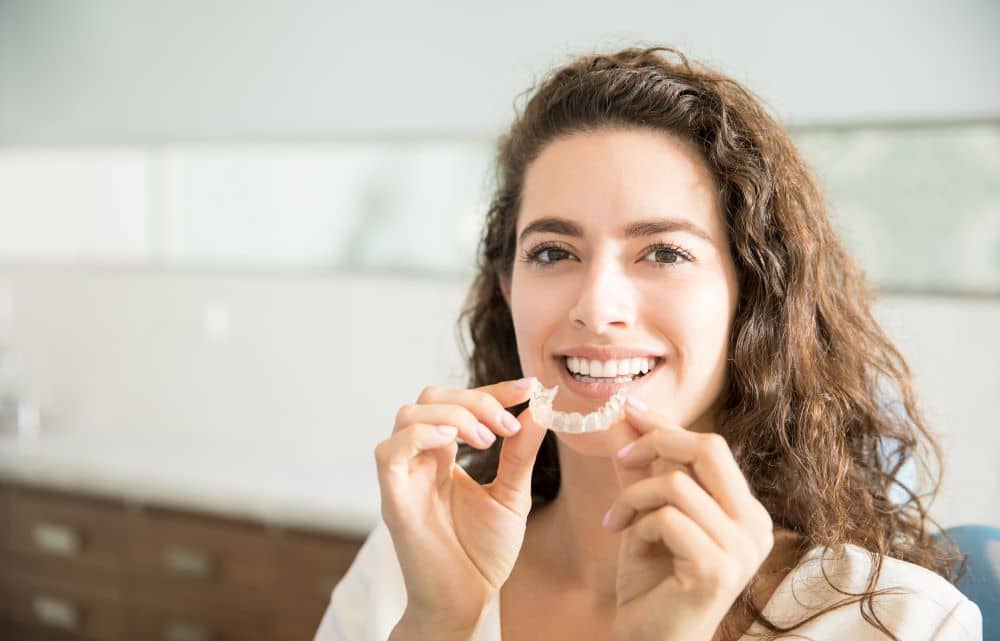 woman putting on aligners at dental clinic