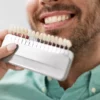 Dentist testing veneer shades by holding veneers against a man's teeth