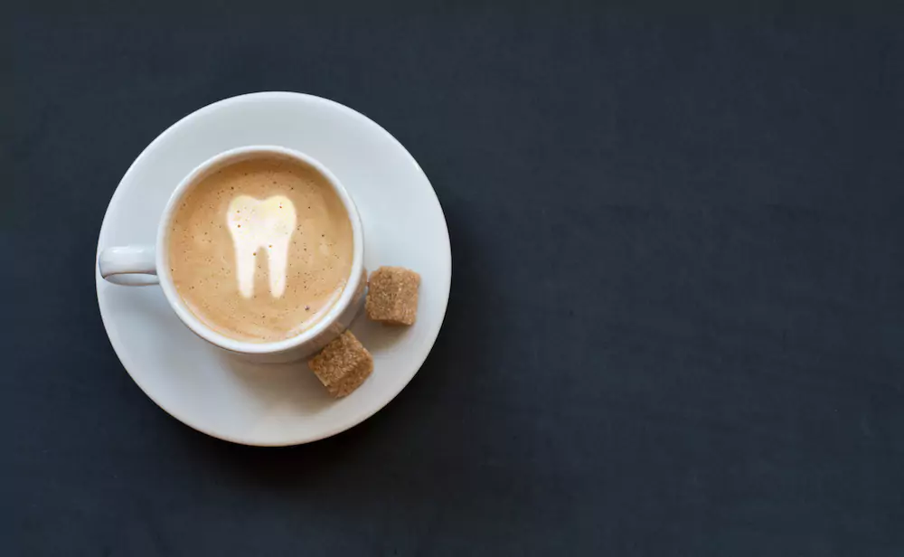 Coffee with a tooth drawn as latte art suggesting it will affect teeth whitening longevity