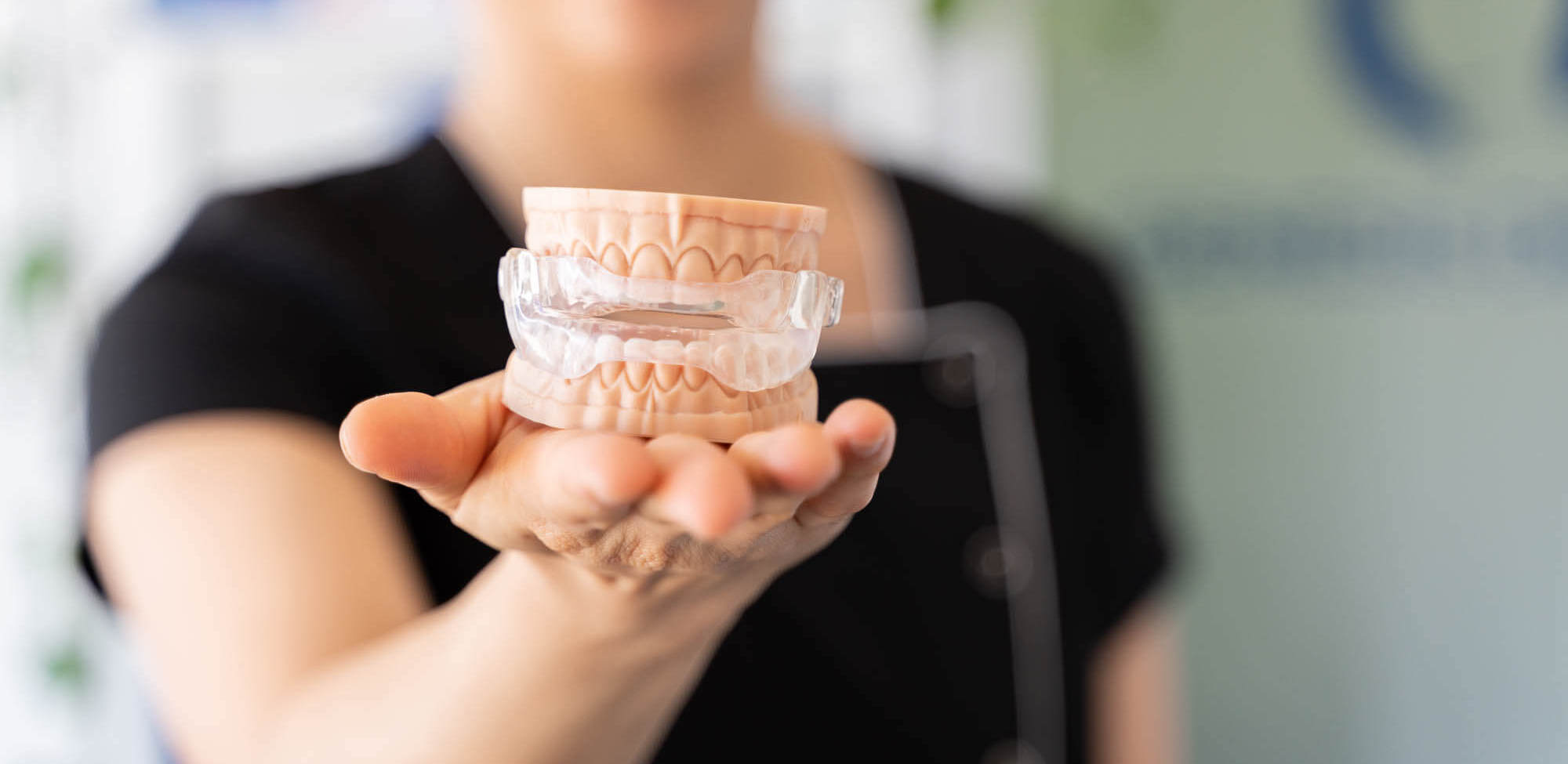 Serene, founder and dentist, holding clear aligners