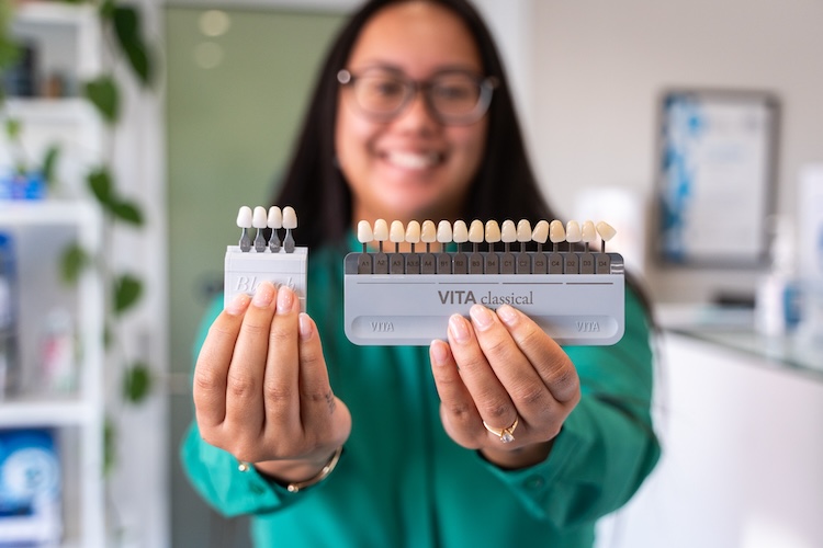 Dentist holding up examples of veneers options in Canning Vale