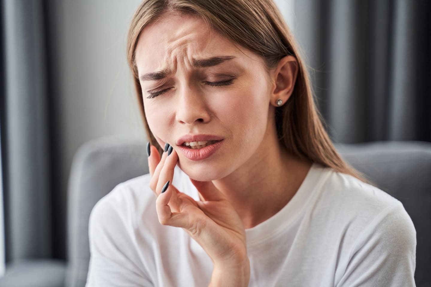 Woman touching cheek waiting to see canker sores dentist in Perth