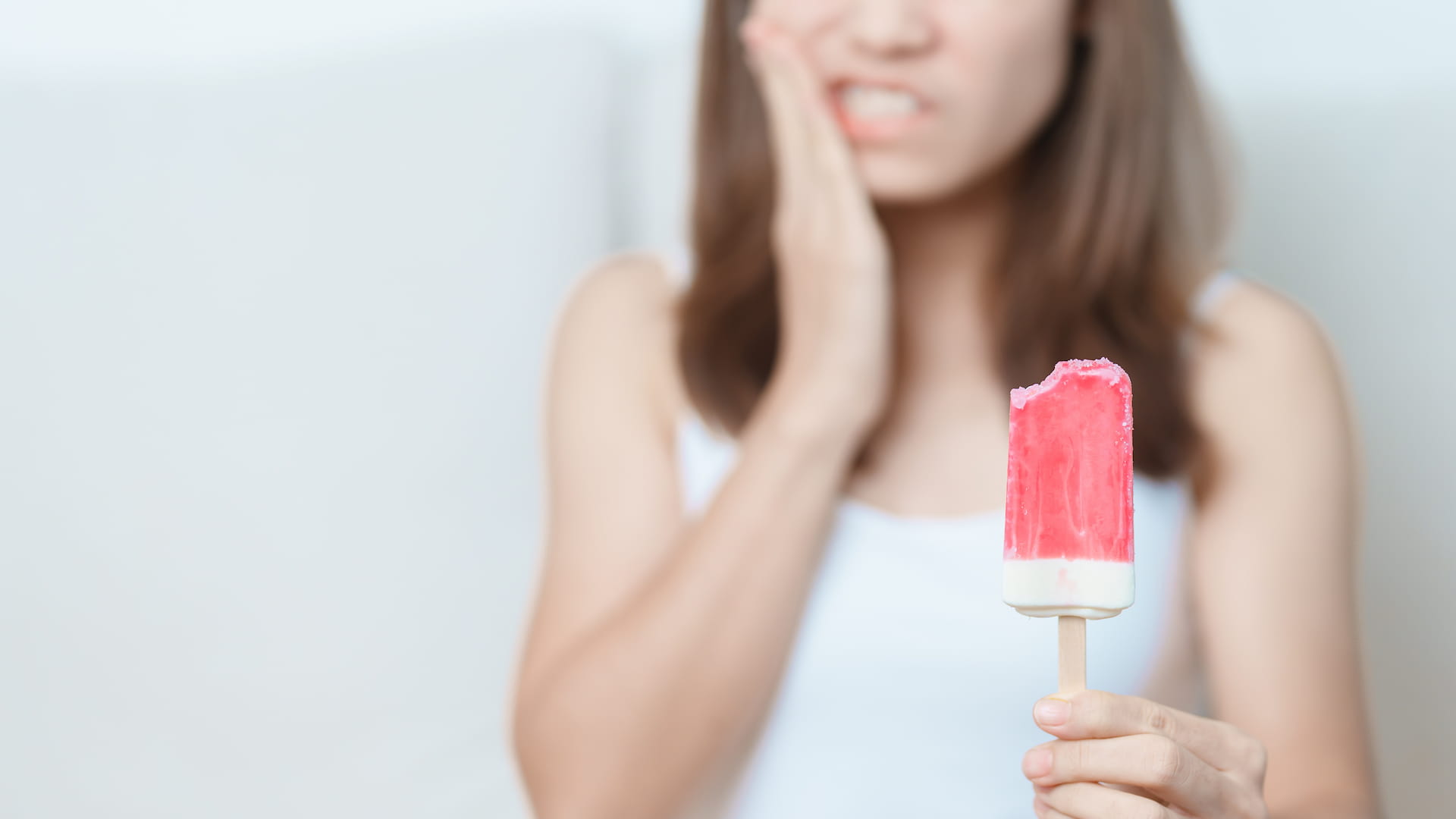 Girl feeling symptoms of cracked teeth after biting cold ice cream