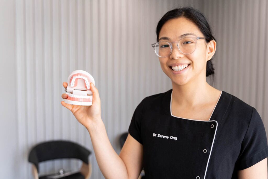 Dentist holding model of teeth and jaw to demonstrate what are malocclusions